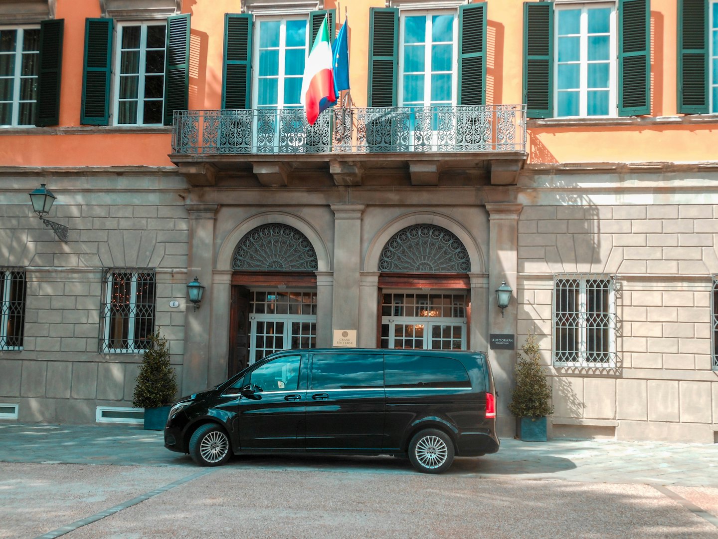 Schwarzer Luxusvan vor einem eleganten europäischen Hotel.