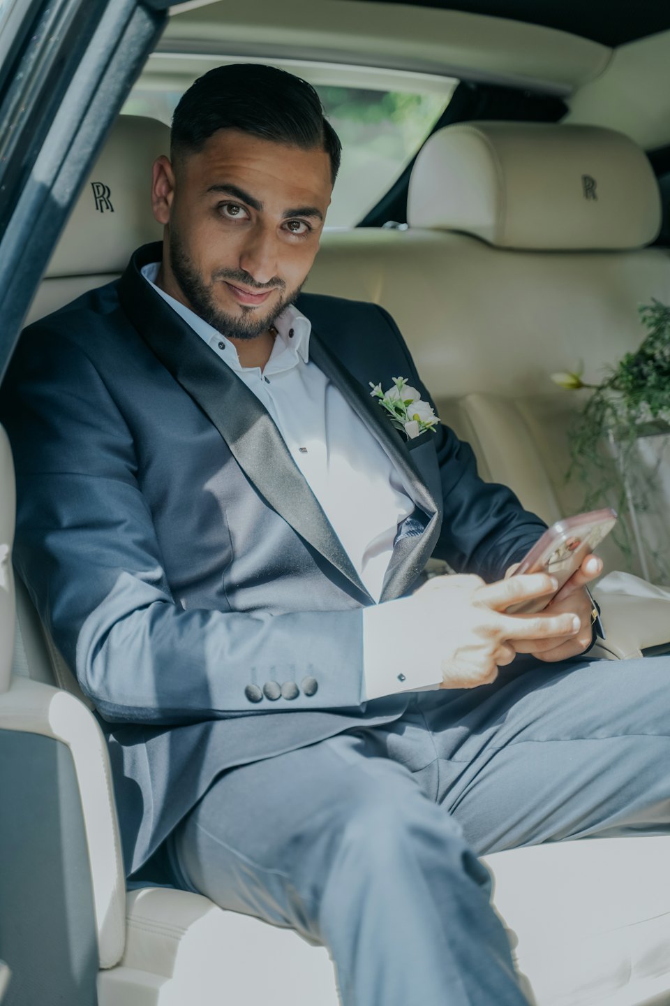 Ein Mann im dunklen Anzug sitzt in einem Luxusauto.
